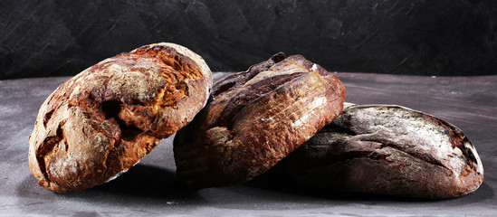 Different kinds of bread and bread rolls on board from above. Kitchen or bakery
