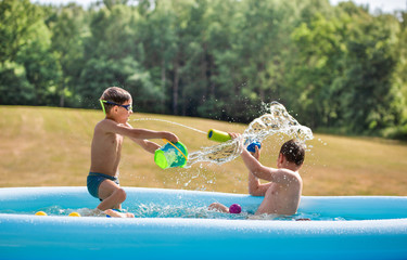 Kids, boys playing with water in a waterpool, vacations, holidays in a polish countryside.