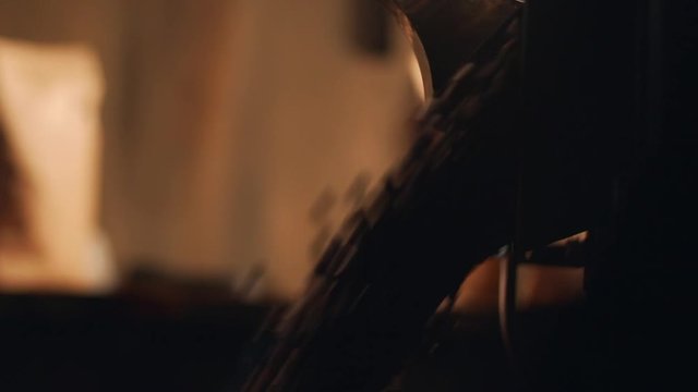 Cropped closeup view of barista man working with roaster machine, roasted arabica coffee beans falling from equipment, in slow motion