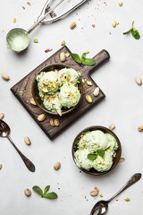 Green pistachio ice cream with mint leaves in brown bowls, top view