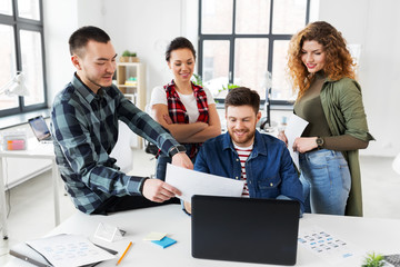 business, technology and people concept - creative team or designers with laptop computer working on user interface at office