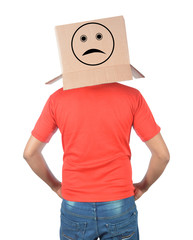 Young man gesturing with a cardboard box on his head with sad face isolated on white background