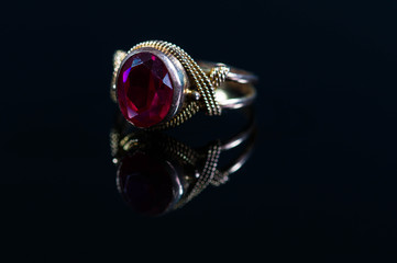 Old, vintage  real gold ring with gem close up macro shot on shiny surface.