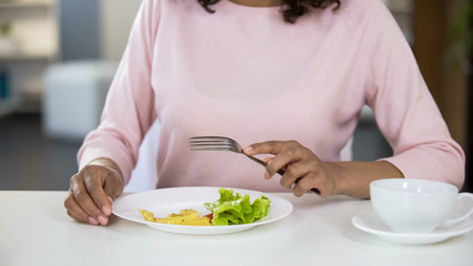 Obraz na płótnie Canvas Biracial woman eating salad, low-calorie nutrition, healthy breakfast, diet