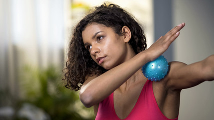 Attractive woman using massaging ball, muscles relaxation, blood circulation