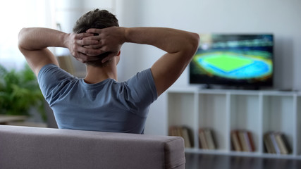 Young man watching soccer match home, criticizing football team for defeat