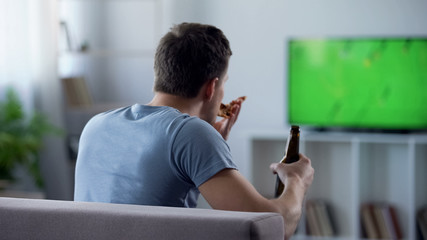 Man watching football match eating snacks and drinking beer on sofa, pastime