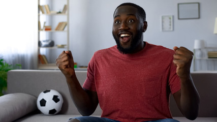 Cheerful sports supporter victoriously screaming watching match on tv, cheering
