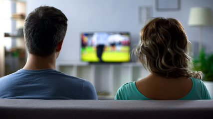 Bored couple watching football match on tv, conflict, passive pastime together