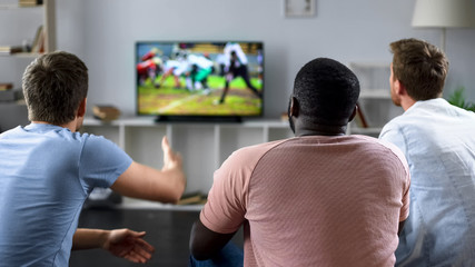 Male friends gather to watch football competition on big screen, sofa experts - 211154974
