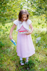 little girl in a light dress holding a blue box