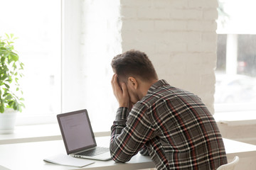 Depressed Caucasian worker feeling down, upset reading negative email about work termination,...