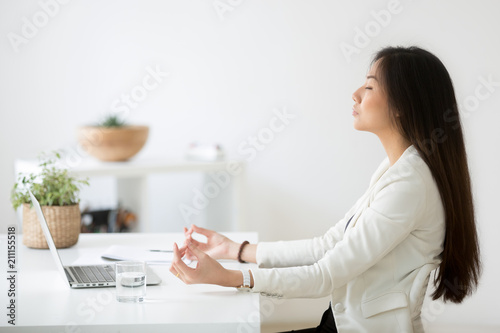 Calm Thoughtful Asian Female Employee Sitting At Office Desk