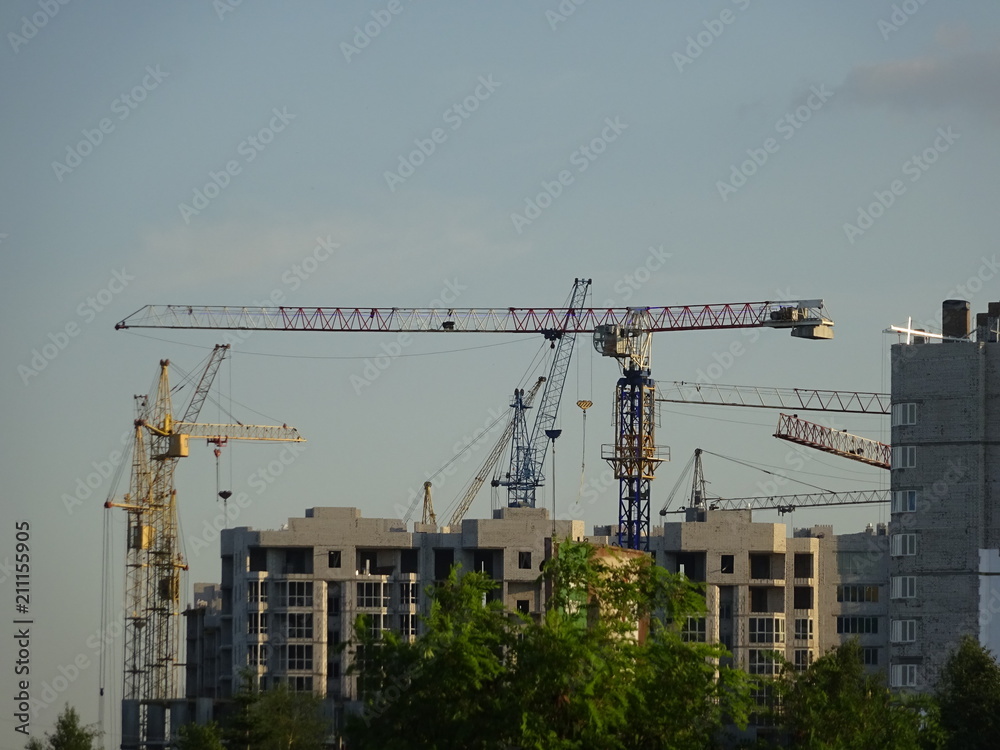 Wall mural A house under construction and a tower crane against the blue sky