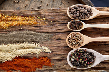 Row of wooden spoons with spices on vintage background, diminishing perspective, close-up, selective focus