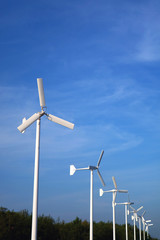 Lined up white wind turbines with blue sky in background  