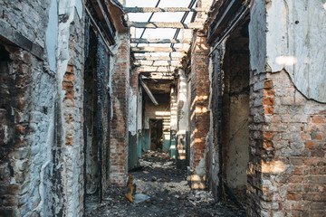 Fototapeta na wymiar Ruins of burned brick house after fire disaster accident. Corridor inside, building without roof, consequences of fire