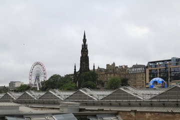 Fototapeta premium Blick auf das Scott Monument und die Altstadt mit Riesenrad, beim öffentlichen Fringe Festival in Edinburgh Schottland