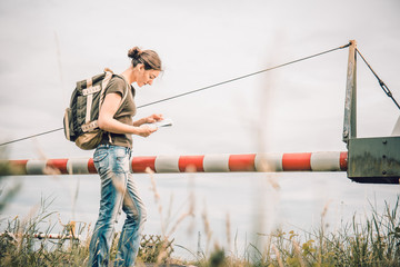 Junge Frau mit Landkarte an einem Bahnübergang in der Natur