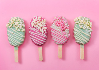 Different cake pops ice creams on pink background.