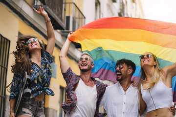 Group of gay friends with a gay pride flag on the street of Madrid city