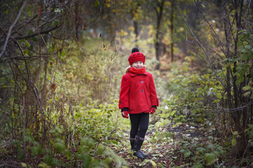 Little girl in a red coat at autumn