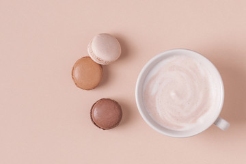 Cup of coffee with macaroons on pastel background.