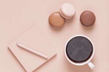 Cup of coffee with macaroons on pastel background.