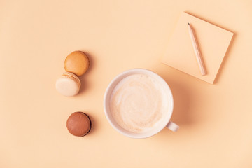 Cup of coffee with macaroons on pastel background.