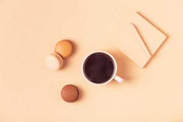 Cup of coffee with macaroons on pastel background.