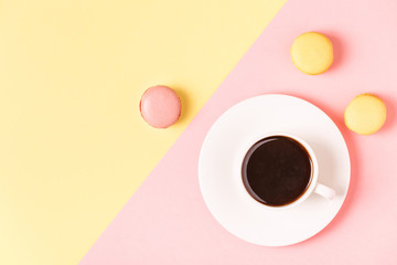 Cup of coffee with macaroons on pastel background.