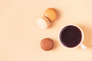 Cup of coffee with macaroons on pastel background.