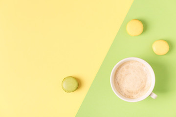 Cup of coffee with macaroons on pastel background.
