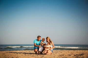 Young happy loving family with small kids having fun at beach together near the ocean, happy lifestyle family concept