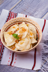 Dumplings, filled with mashed potato - vegetarian dish. Varenyky, vareniki, pierogi, pyrohy in a bowl on wooden table. vertical