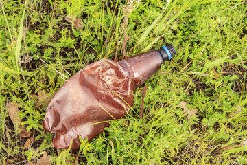 Empty plastic bottle on green grass. Concept of environmental protection