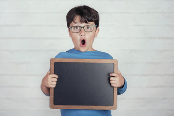surprised boy with a blackboard on brick background