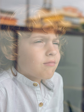 Sad little boy looking through glass