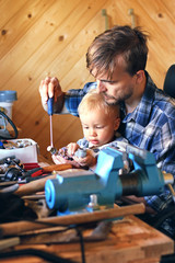 Father and son in workshop repairing some stuff. Cute boy exploring tools.