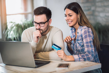 Smiling couple using digital tablet and credit card at home