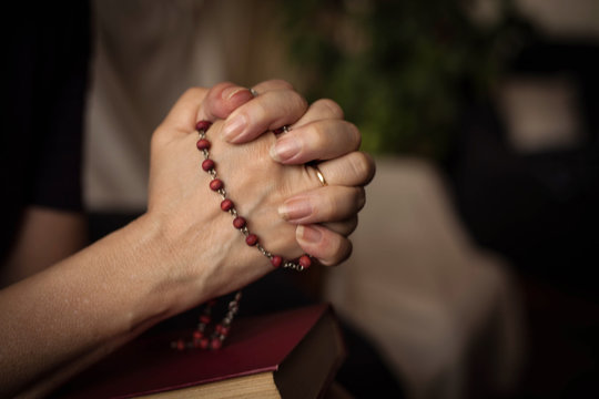 Hands with rosary and an old book