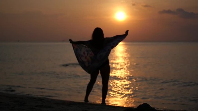 A chic sexy girl in a dress whirls on the beach at sunset. HD, 1920x1080, slow motion