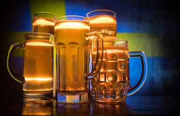 Creative concept. Beer glasses on table at dark toned foggy background with blurred view of flag of Sweden. Support your country with beer concept.