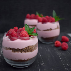 Sweet raspberry mousse in glass bowl on dark background