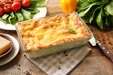 Baking tray with spinach lasagna on wooden table