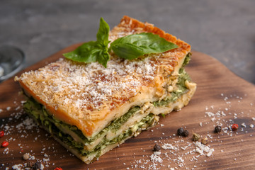 Lasagna with spinach on wooden board, close up