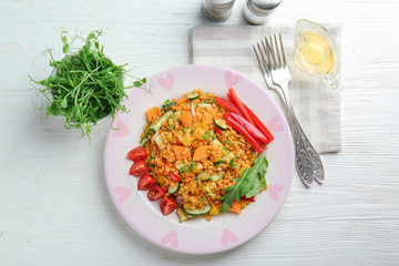 Plate with delicious lentils salad on wooden table