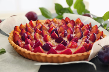 Delicious pie with plums on table