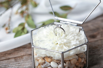 Beautiful engagement ring with flower in glass box on table