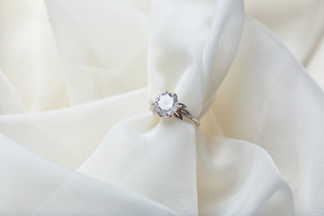 Obraz na płótnie Canvas Beautiful engagement ring on light fabric, closeup